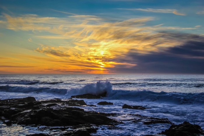 Ocean waves crashing on rocks at sunset
