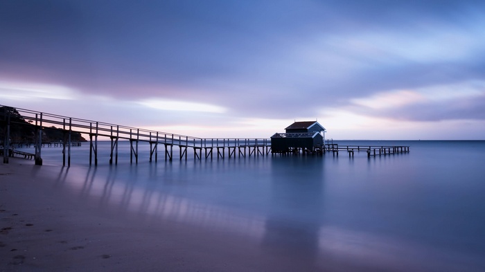 Wooden jetty extending into the calm ocean at sunset