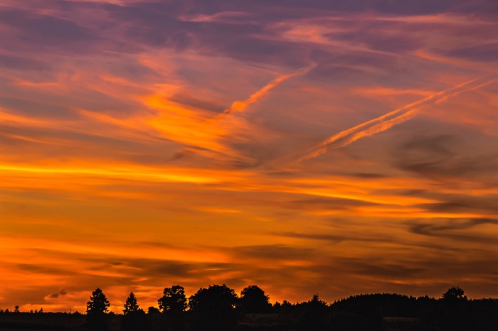 Sunset clouds over a silhouetted landscape