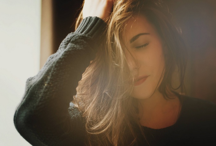 A woman in a sweater with her hand in her hair