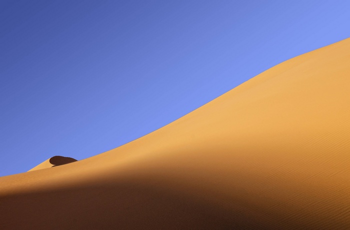 Desert sand dunes under a clear blue sky