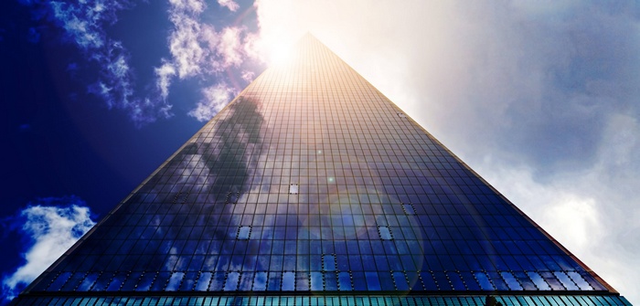 Glass Skyscraper Facade Reflecting Clouds and Sun