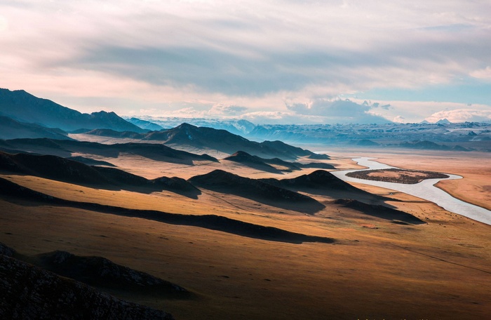 River flowing through a vast mountain landscape with rolling hills