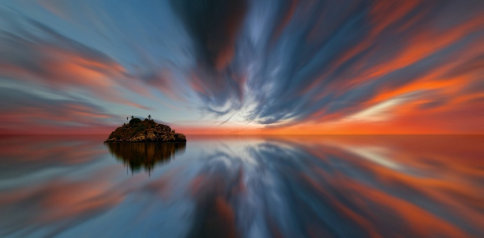 Island in the ocean during sunset with reflection