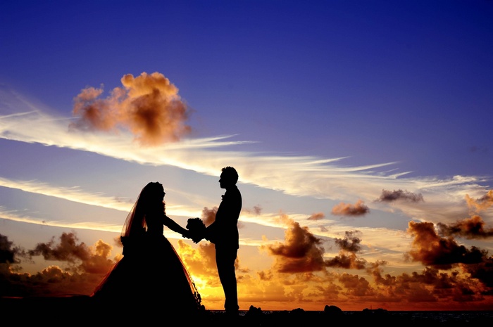 Bride and groom silhouetted against a sunset