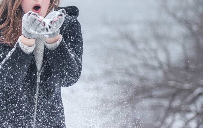 Woman blowing snow in winter