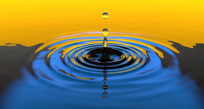 Water drop creating ripples on a yellow and blue surface