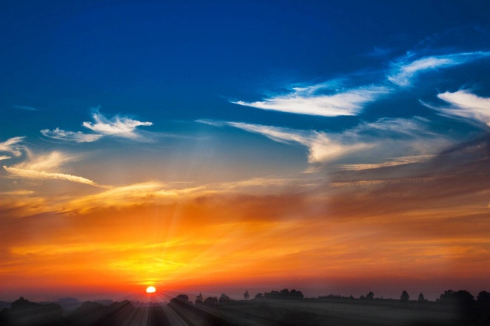 Sunset with sunbeams over a misty landscape