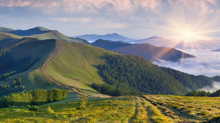 Sunrise over misty mountains with rolling green hills