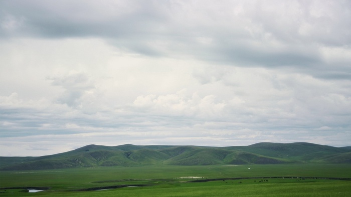 Green rolling hills under a cloudy sky