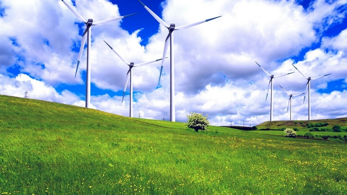 Wind turbines on a grassy hill under a cloudy sky