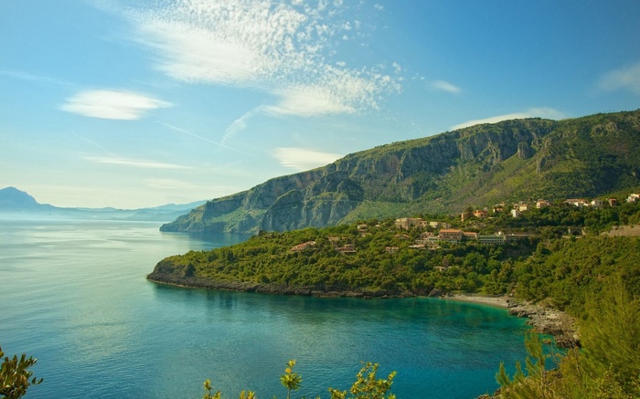 Coastal village nestled on a green mountainside overlooking the sea