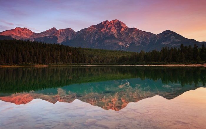Mountain range reflected in a calm lake at sunset