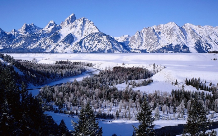 Snowy mountains and forest with a river