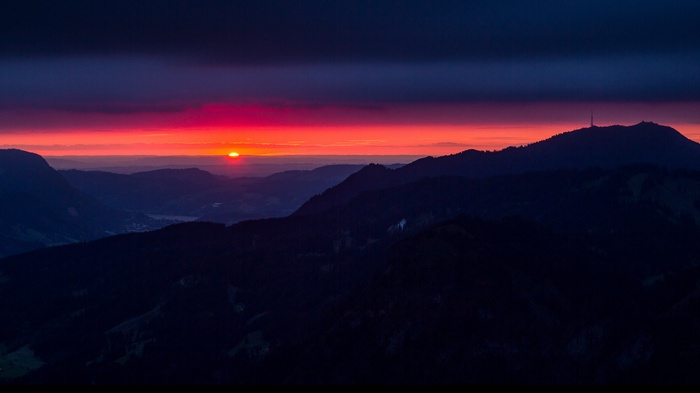 Sunset over mountain ranges with a radio tower