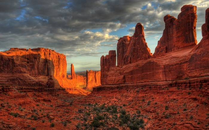 Red rock formations under a cloudy sky at sunset