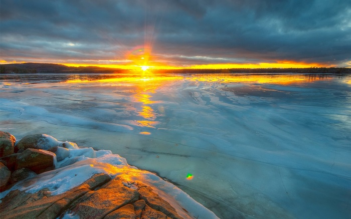 Sunset over a frozen lake with rocky shore