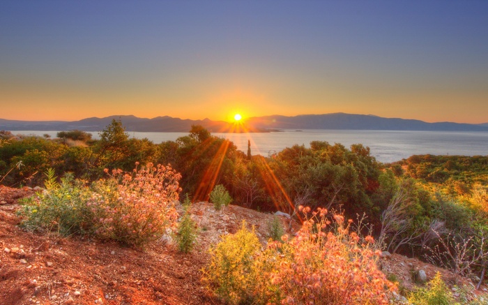 Sunset over the sea with mountains and vegetation