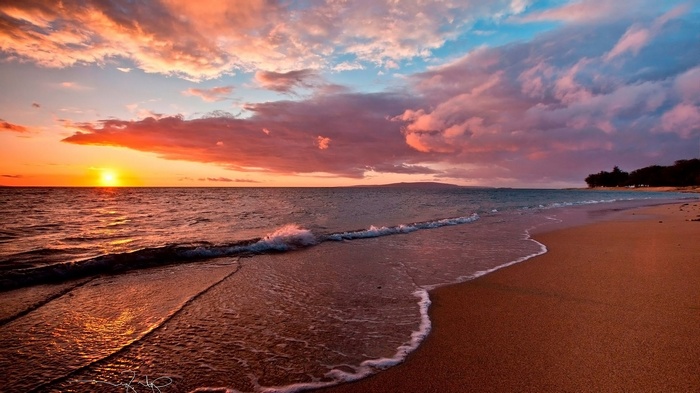 Sunset over the ocean with colorful clouds and beach