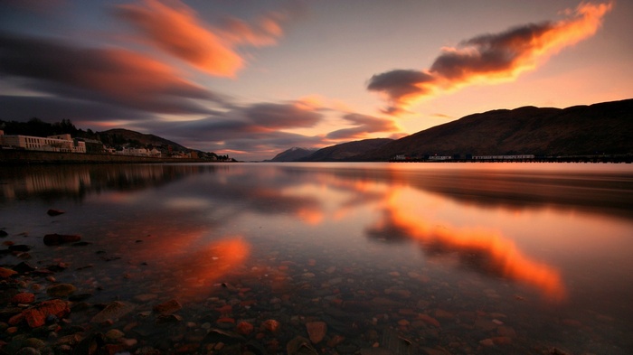 Sunset over a calm lake with mountains and a town