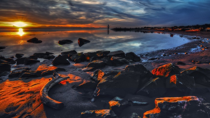 Sunset over a rocky beach with calm water
