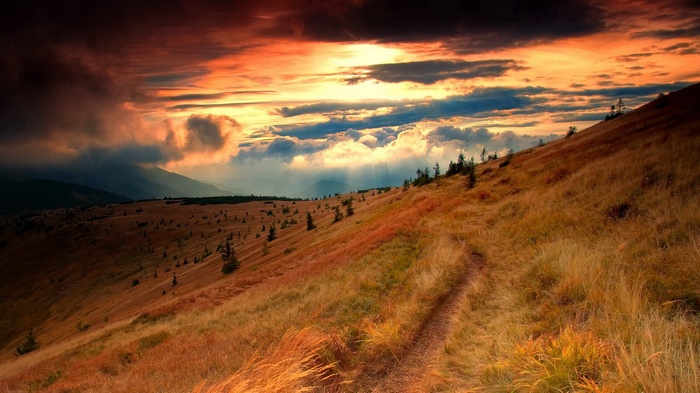 Mountain slope with a path at sunset