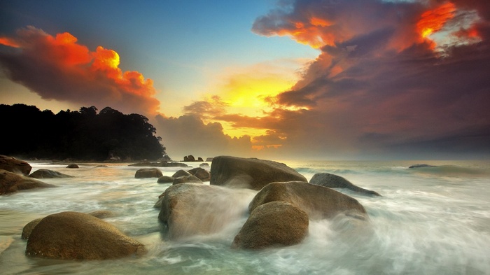 Sunset over rocky beach with ocean waves