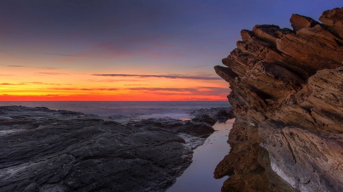 Rocky coastline at sunset with ocean waves