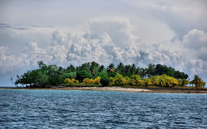 Island with palm trees and clouds over the ocean