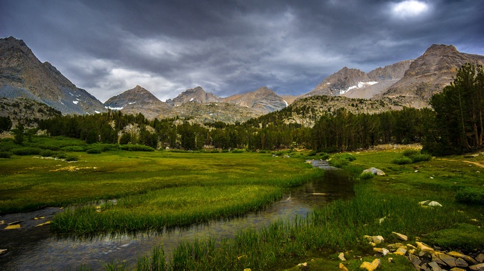 Mountain landscape with stream and stormy sky