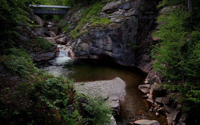 Covered bridge over a rocky gorge with a waterfall