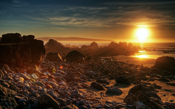 Sunset over rocky beach with ocean waves