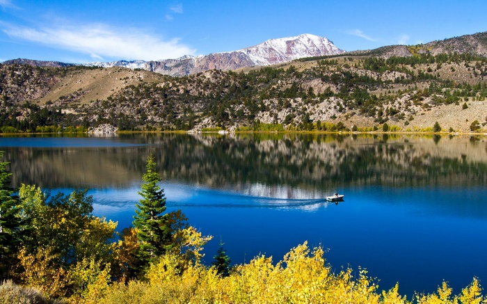 Boat on a lake with mountains and autumn trees