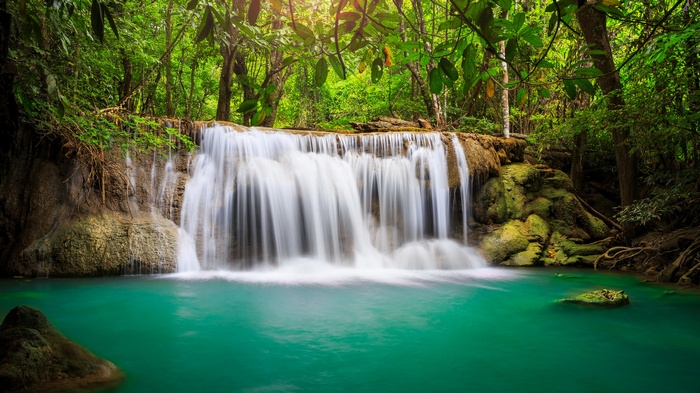 Waterfall in a lush green forest with turquoise water