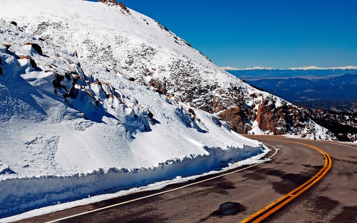 Winding mountain road with snow and distant mountains