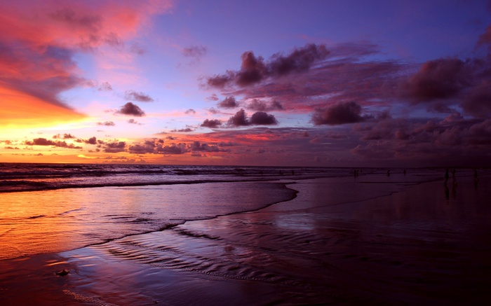 Sunset over a beach with colorful clouds and reflections