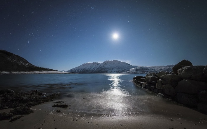 Moonlit night over snowy mountains and a calm lake