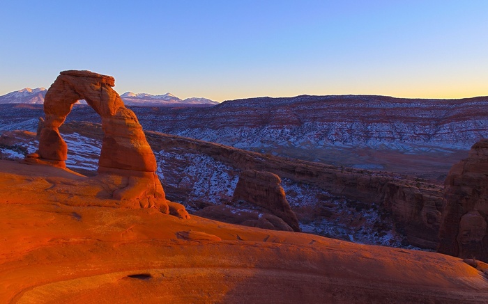 Delicate Arch at sunrise with snow-capped mountains
