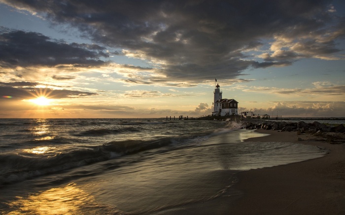 Lighthouse on a rocky shore at sunset