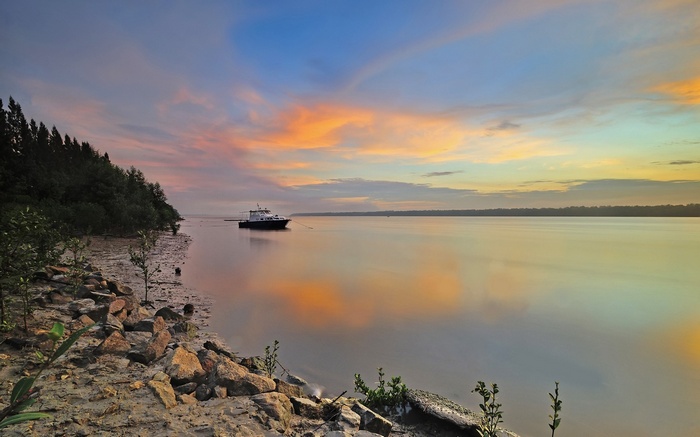Boat on calm water at sunset with colorful sky