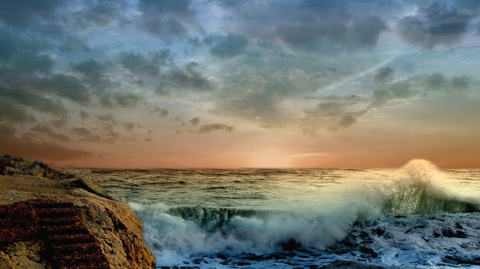 Ocean waves crashing on rocks at sunset