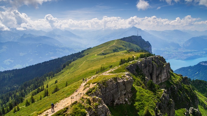 Hikers on a mountain ridge overlooking a lake and distant mountains