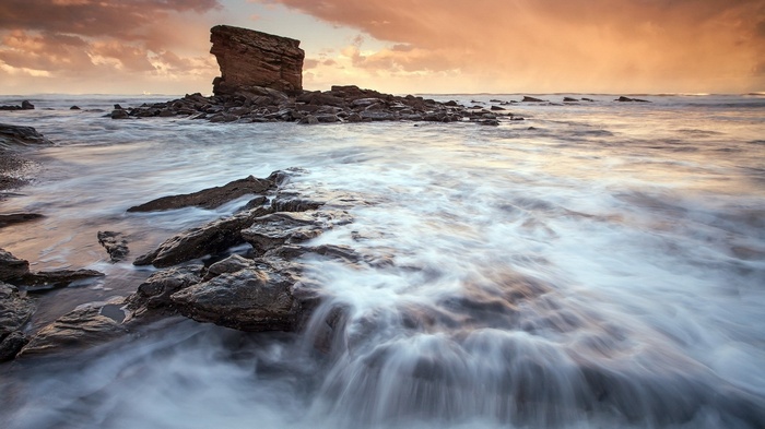 Rocky coastline with waves at sunset