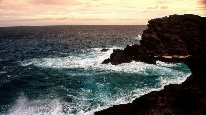 Waves crashing against rocky cliffs at sunset