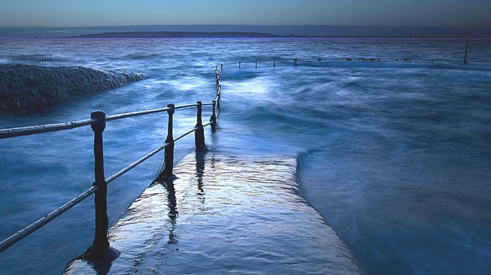 Ocean swimming pool with railing at dusk