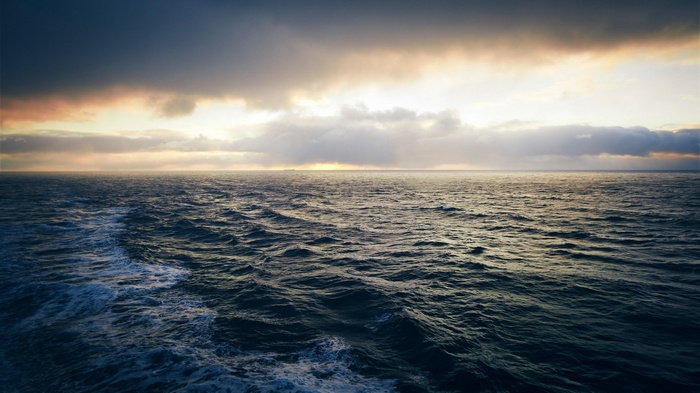 Ocean waves under cloudy sky at sunset
