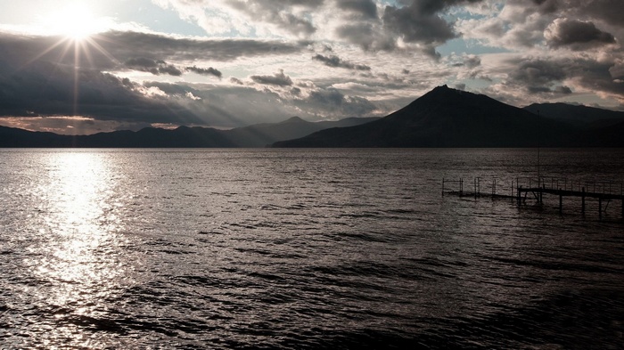 Sunset over a lake with mountains and a pier