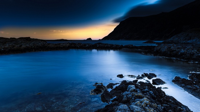 Rocky coastline with calm blue water at dusk