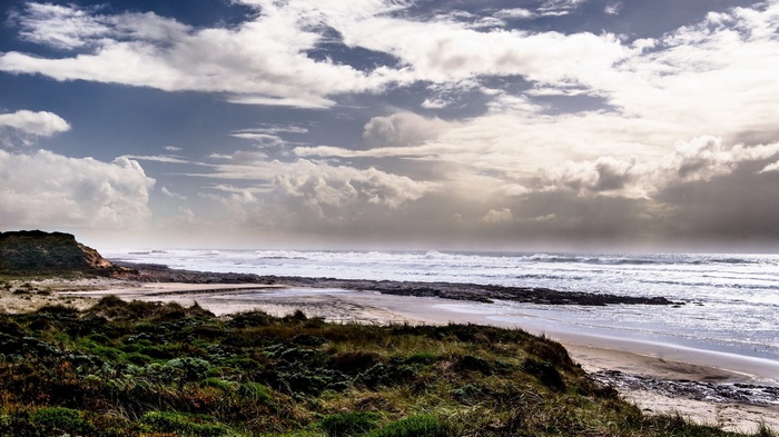 Ocean waves crash on a rocky shore under a cloudy sky