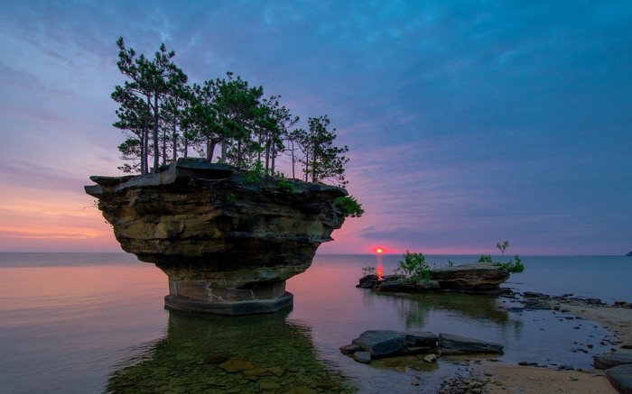 Sunrise over rock formations with trees in water